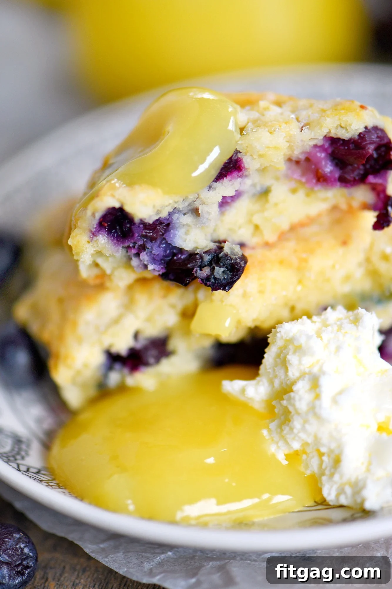 Delectable lemon blueberry scones served with generous dollops of lemon curd and whipped cream on a elegant serving plate