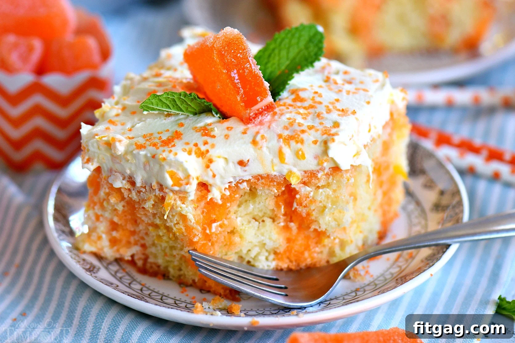 Orange Blossom Cream Cake 2 A delectable square slice of orange creamsicle cake on a small white plate, with a bite taken, revealing the moist vanilla cake and vibrant orange JELL-O infusion underneath the fluffy frosting.