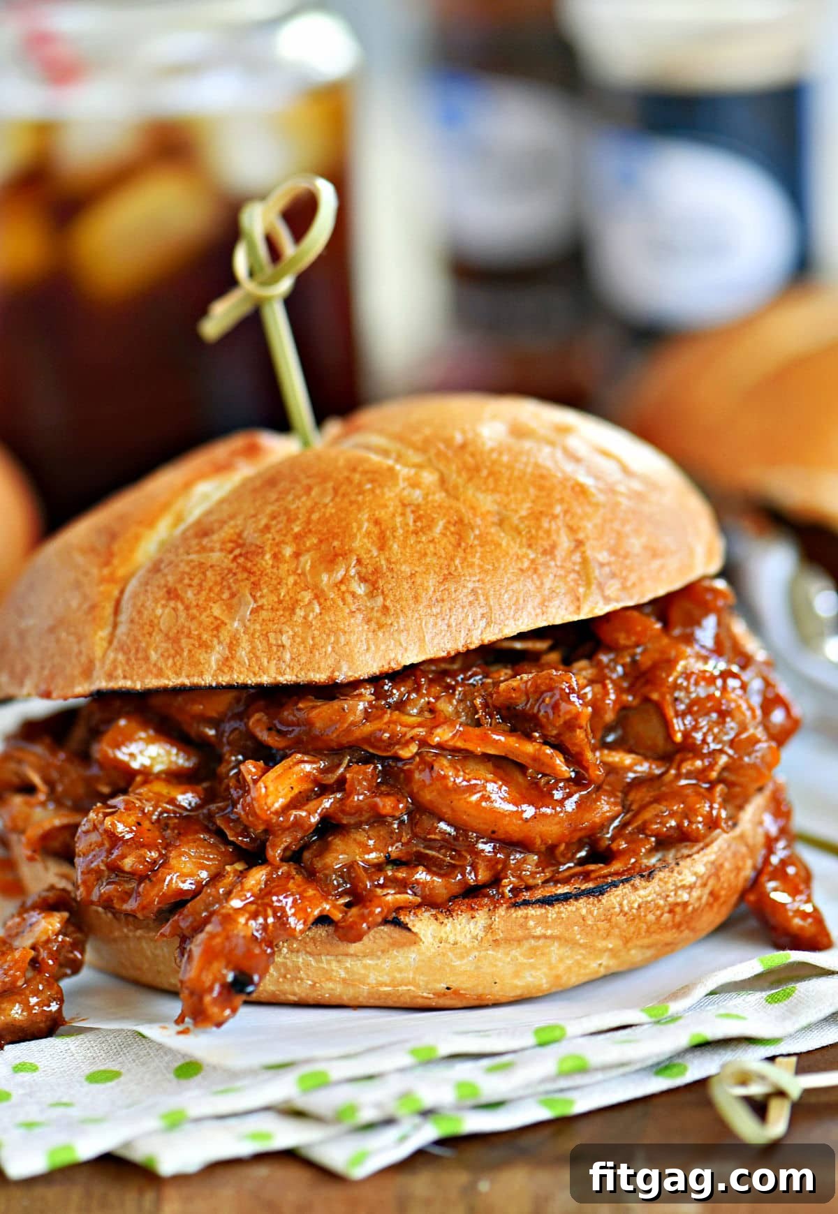 A delicious BBQ pulled chicken sandwich sitting on a charming green and white napkin, ready to be enjoyed.