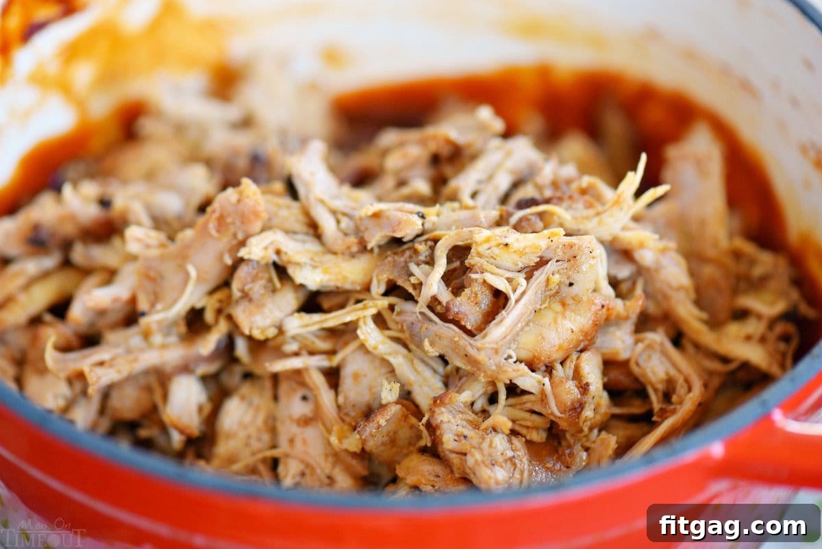 Delicious pulled chicken about to be stirred into a bubbling pot of homemade root beer bbq sauce, ready to be coated in flavor.