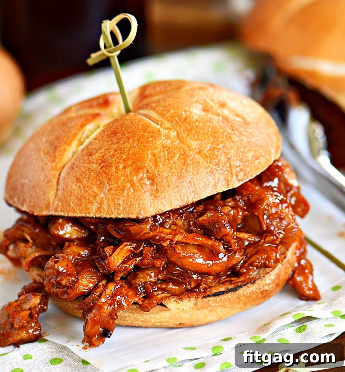 A mouthwatering BBQ pulled chicken sandwich served on a perfectly toasted bun, secured with a festive toothpick through the top bun, ready for a delicious bite.