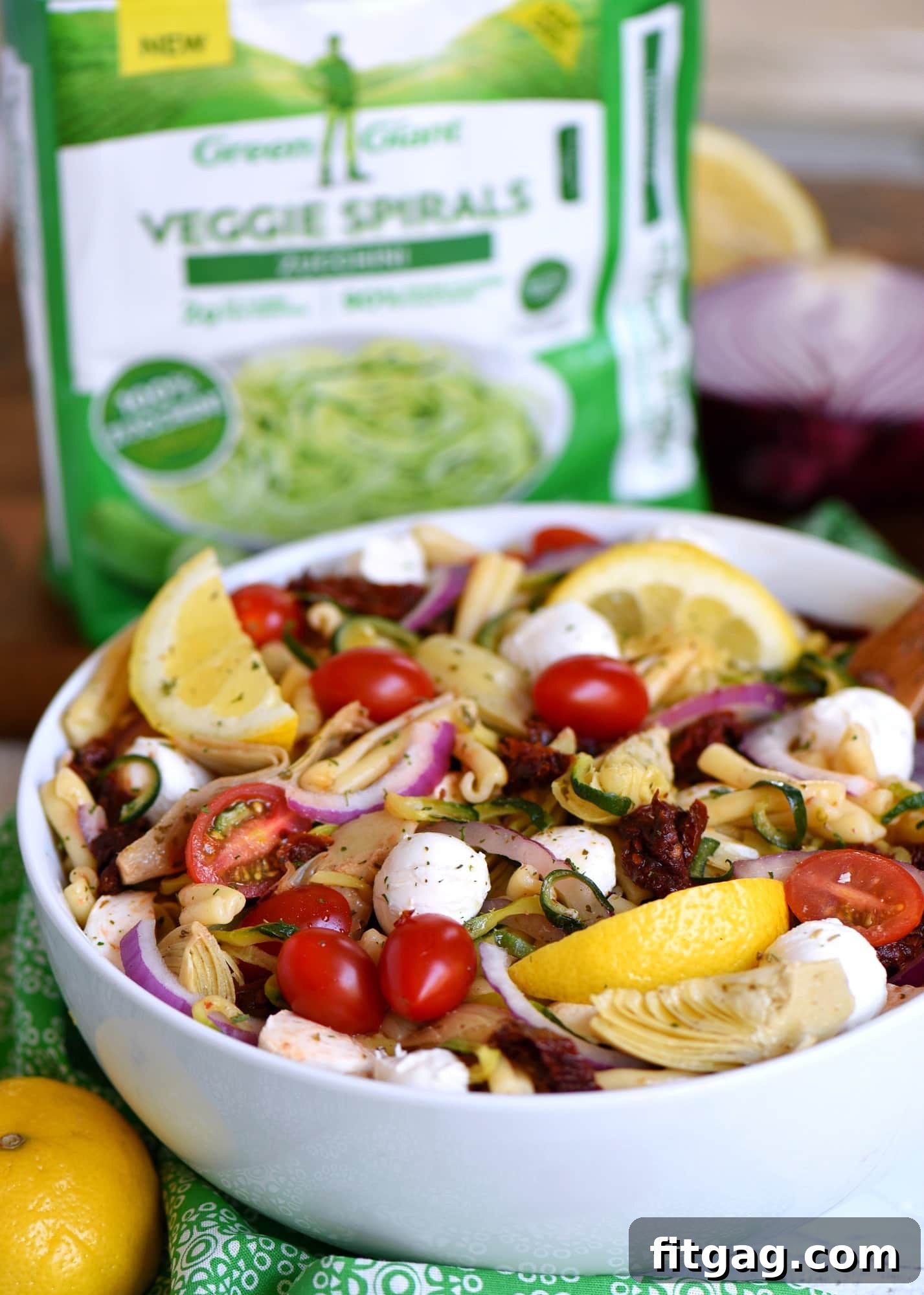 Serving bowl of Zucchini Pasta Salad with Sun Dried Tomatoes and Mozzarella, garnished with fresh herbs.