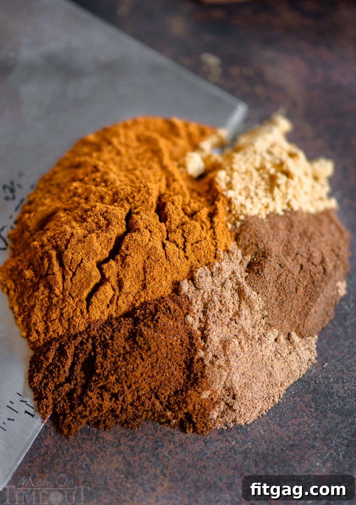 Pumpkin pie spice recipe ingredients being bench scraped off a surface ready to be mixed together and placed in an airtight jar.