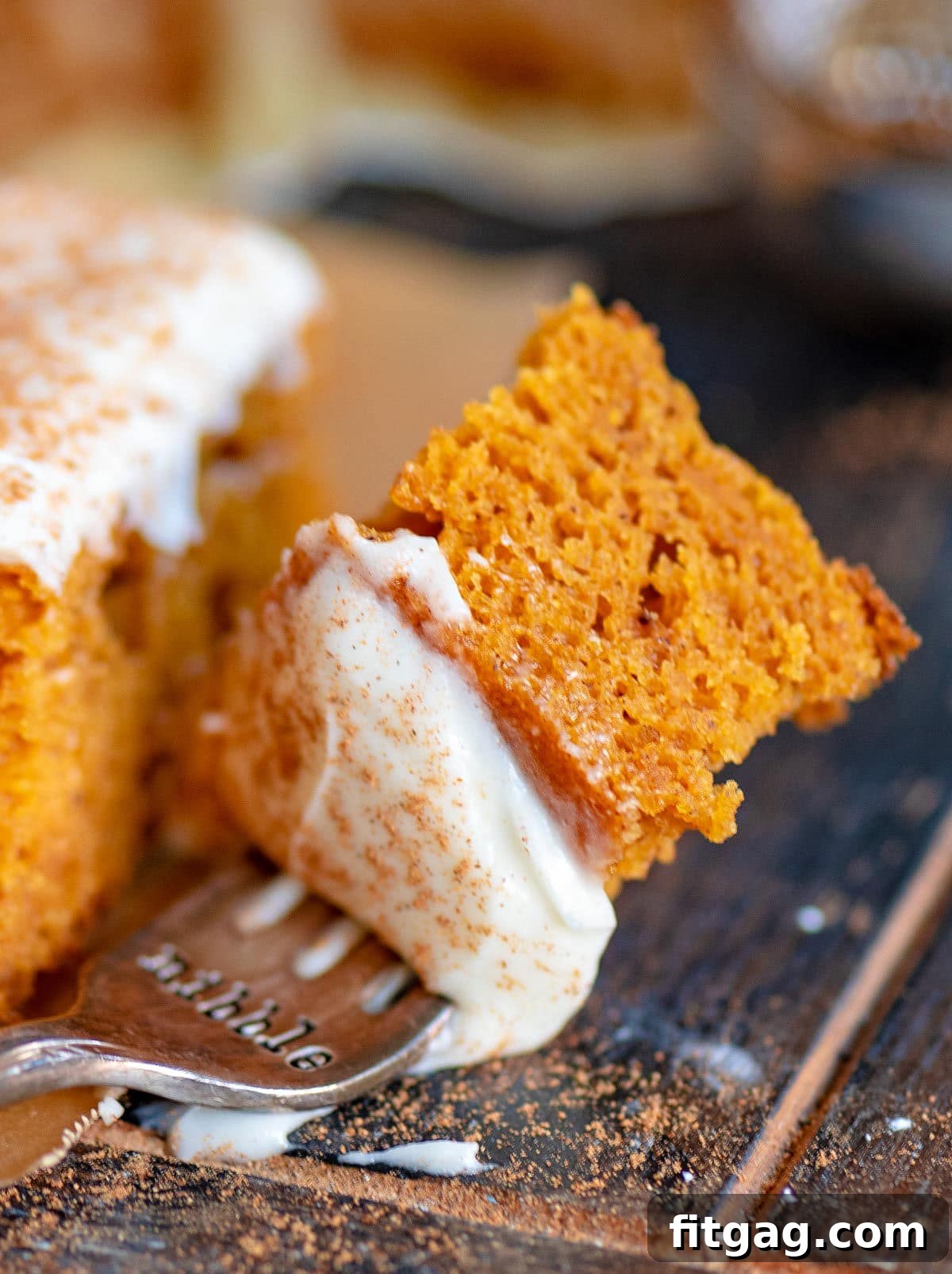 Dreamy Spiced Pumpkin Bars 3 A single bite of pumpkin bar on a silver fork, showing the moist cake and creamy frosting.