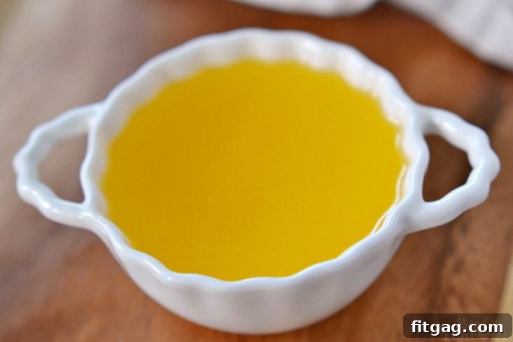 Golden clarified butter cooling in a glass jar, showcasing its clear, pure state.