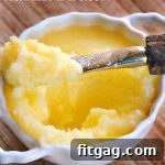 Final product of clarified butter in a glass jar, next to a block of unsalted butter.
