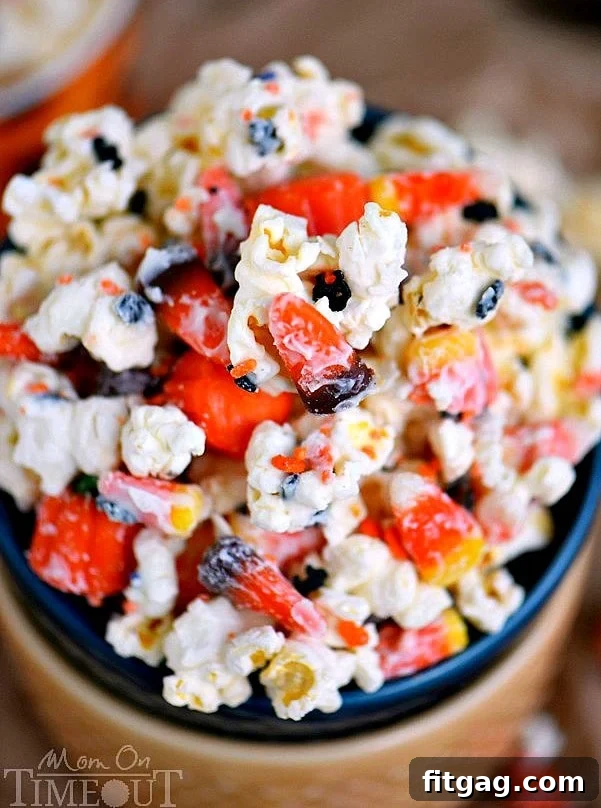 A large bowl of Halloween snack mix, featuring popcorn, candy corn, and sprinkles.