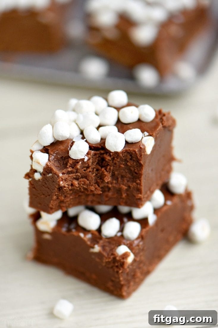 A tray of hot cocoa fudge squares, topped with mini marshmallows, cut and ready to be enjoyed as a delightful dessert.