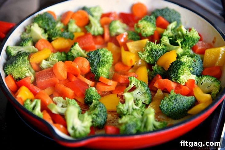 Colorful chicken stir fry served fresh from the pan, featuring tender chicken, bright green broccoli, and vibrant red and yellow bell peppers alongside carrots.