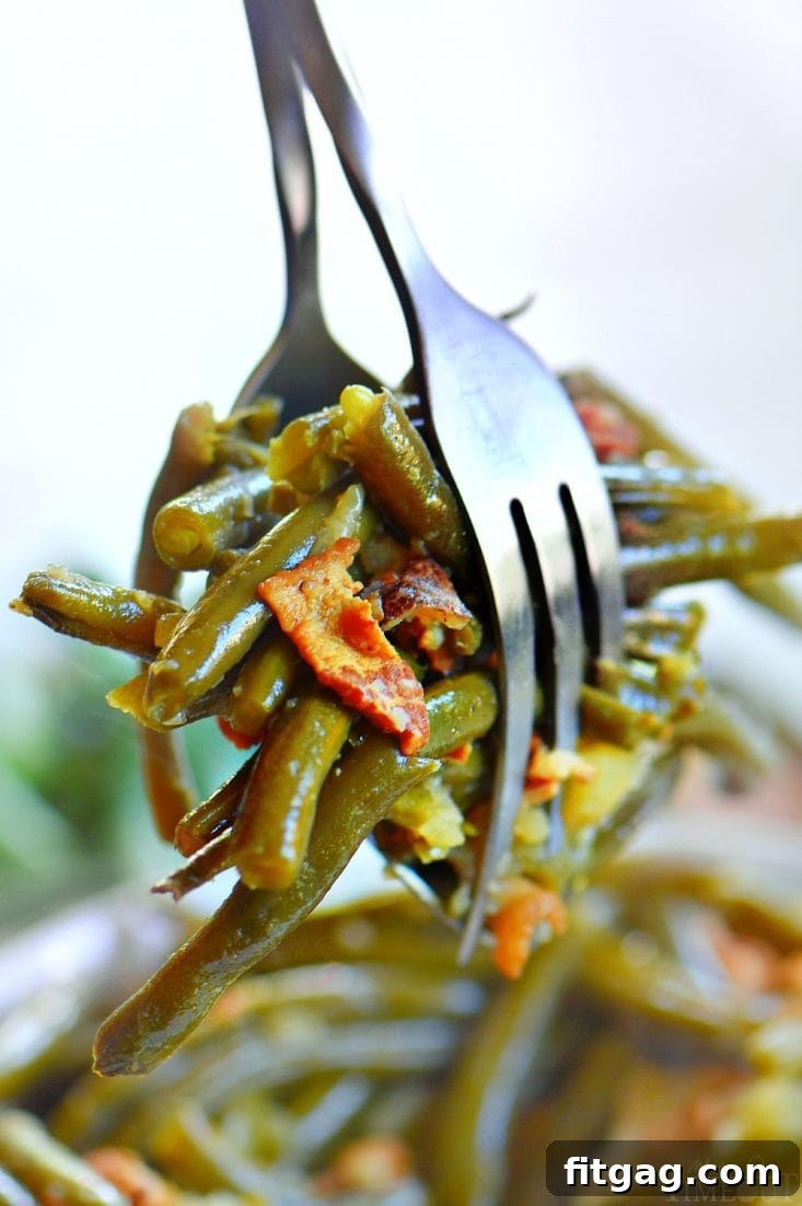 Close-up of southern-style crockpot green beans with bacon and potatoes, highlighting the rich flavors and tender texture of this comforting side dish.