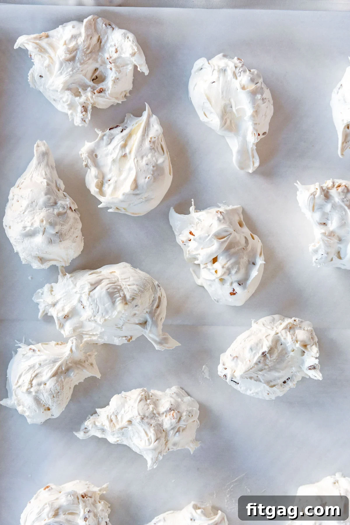Individual pieces of divinity candy carefully drying on a piece of parchment paper.