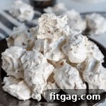 A silver plate piled high with delicate, white divinity candy, with one piece broken in half to reveal its soft texture.