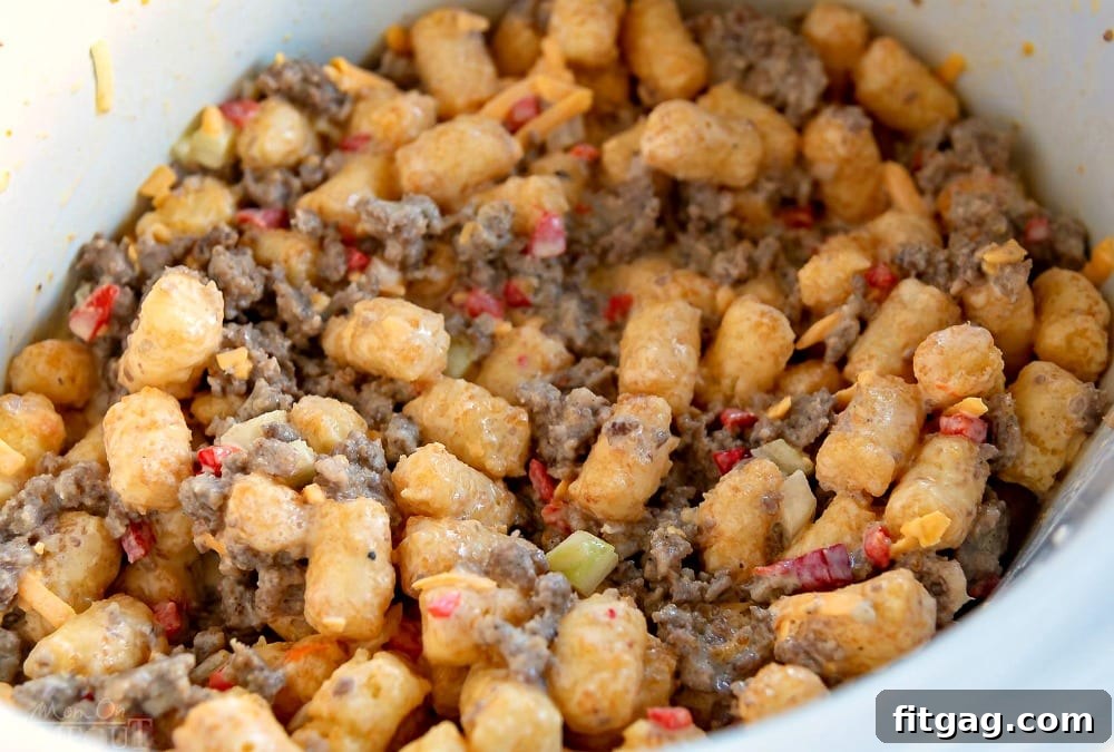 Raw ingredients for Slow Cooker Tater Tot Breakfast Casserole, including eggs, cheese, sausage, and tater tots, layered in the slow cooker before cooking.