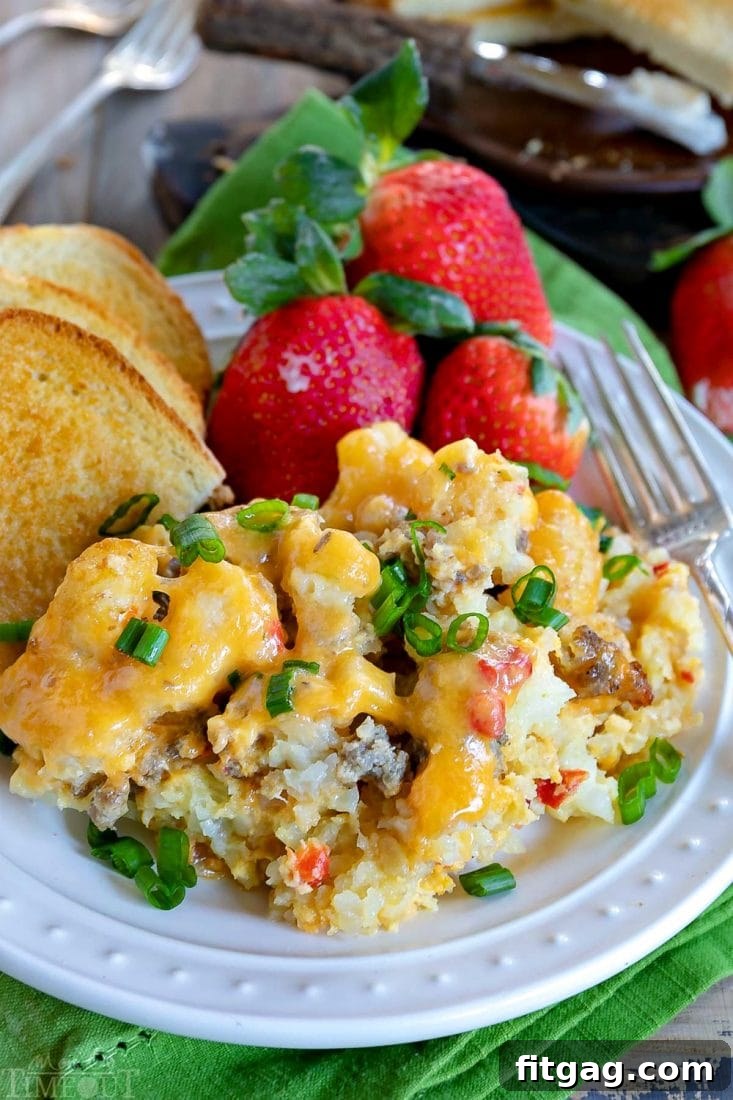 A close-up of a serving of Tater Tot Breakfast Casserole garnished with fresh green onions, showcasing the perfect blend of sausage, eggs, and cheese.