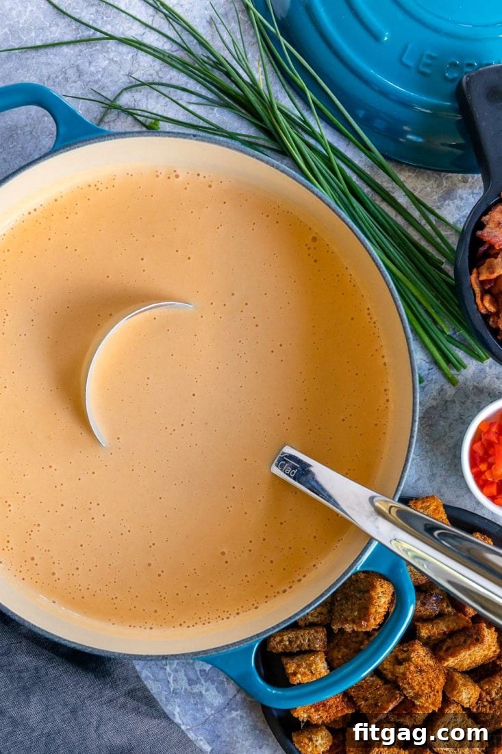 Beer Cheese Soup simmering in a large pot, with a ladle resting inside, ready to be served.