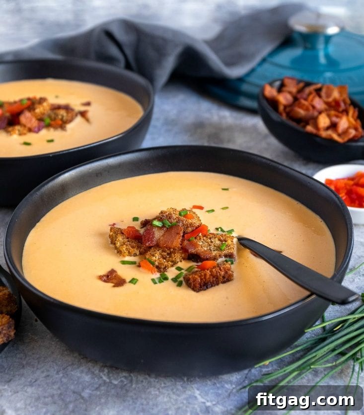 Easy Beer Cheese Soup recipe served in a black bowl, beautifully garnished with toppings.