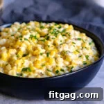 black bowl of creamed corn with chives snipped on top.