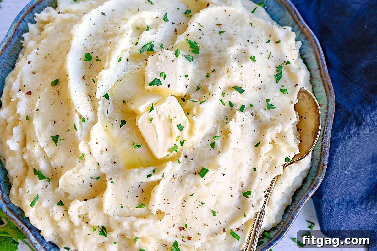 top down close up look at mashed potato recipe in a shallow bowl with butter and parsley.