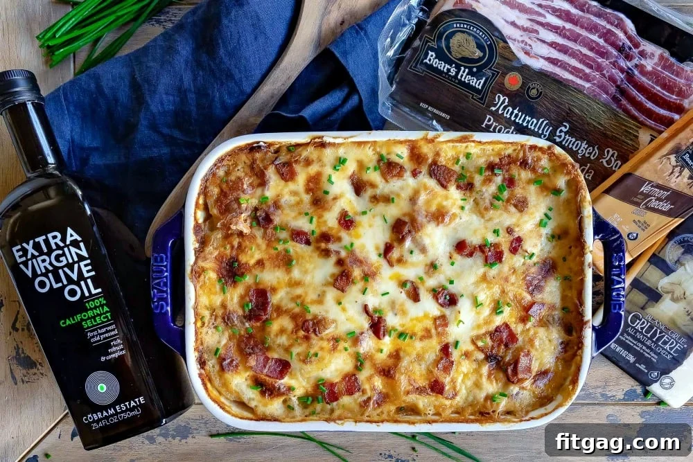 All fresh ingredients for loaded scalloped potatoes laid out on a wooden board: thinly sliced potatoes, blocks of cheese, crispy bacon, whole milk, butter, sliced onions, and a bottle of olive oil.