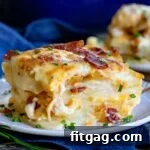 serving of scalloped potatoes made with bacon and onion on a small white plate with a blue napkin underneath it.