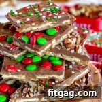 Christmas Toffee Craze 7 Square pieces of Christmas Crack cut and stacked on a round wood board. The toffee is topped with candy and sprinkles.