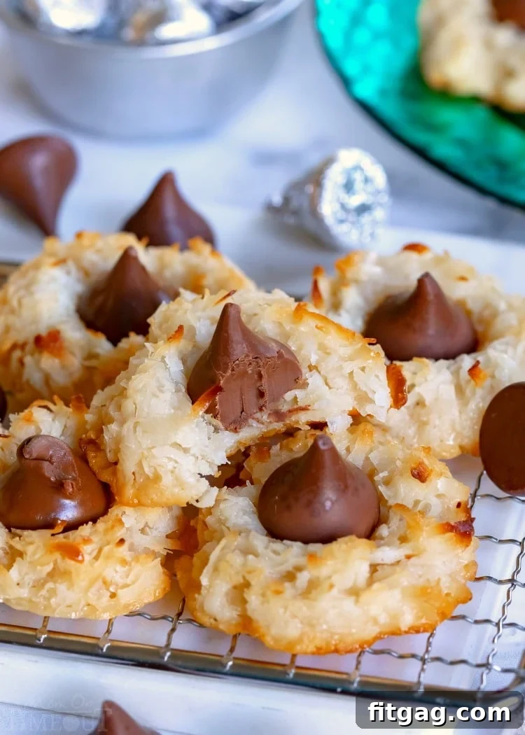 Freshly baked Coconut Macaroon Blossoms cooling on a wire rack, one with a bite taken out.