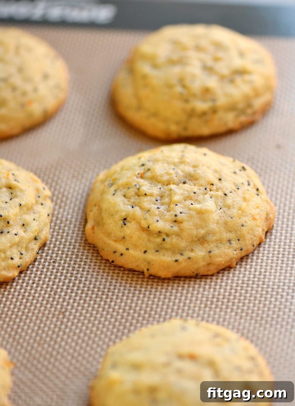 These easy Glazed Orange Poppy Seed Cookies are bursting with orange flavor! So soft and tender, these cookies will quickly become a new favorite! Bonus: no chill time needed! // Mom On Timeout #cookies #orange #poppyseed #easy #baking #dessert orange poppy seed cookies on silicone baking mat baked