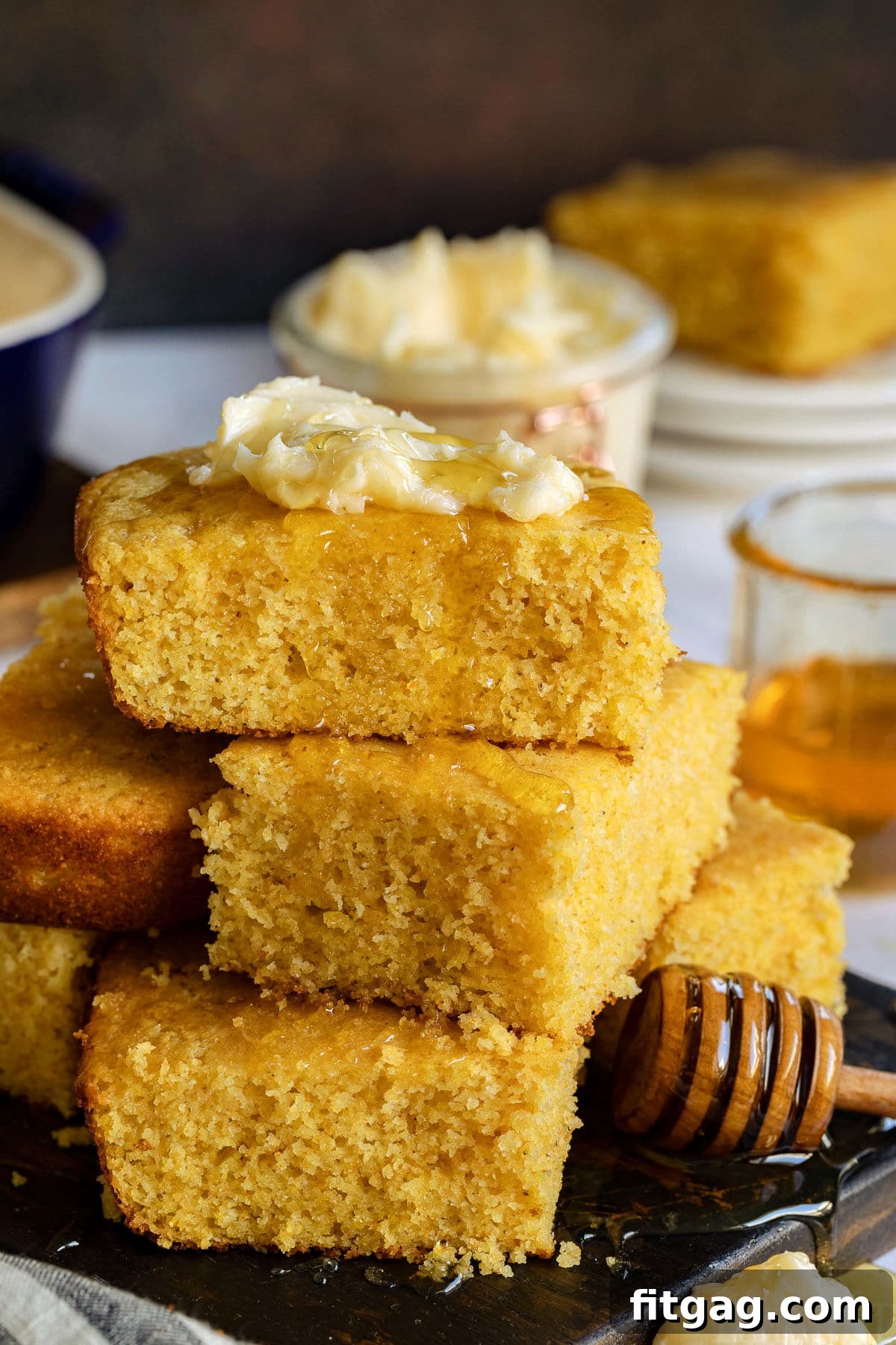 The BEST Honey Butter is ridiculously easy to make and tastes amazing! With just 4 ingredients, this homemade honey butter recipe is perfectly sweet and creamy and is incredible smeared on cornbread, biscuits and homemade dinner rolls! // Mom On Timeout #honeybutter #honeybutterrecipe #homemade #condiments #butter #honey Warm cornbread recipe stacked high, with generous amounts of honey drizzling over the top and a dollop of creamy honey butter, ready to be enjoyed.