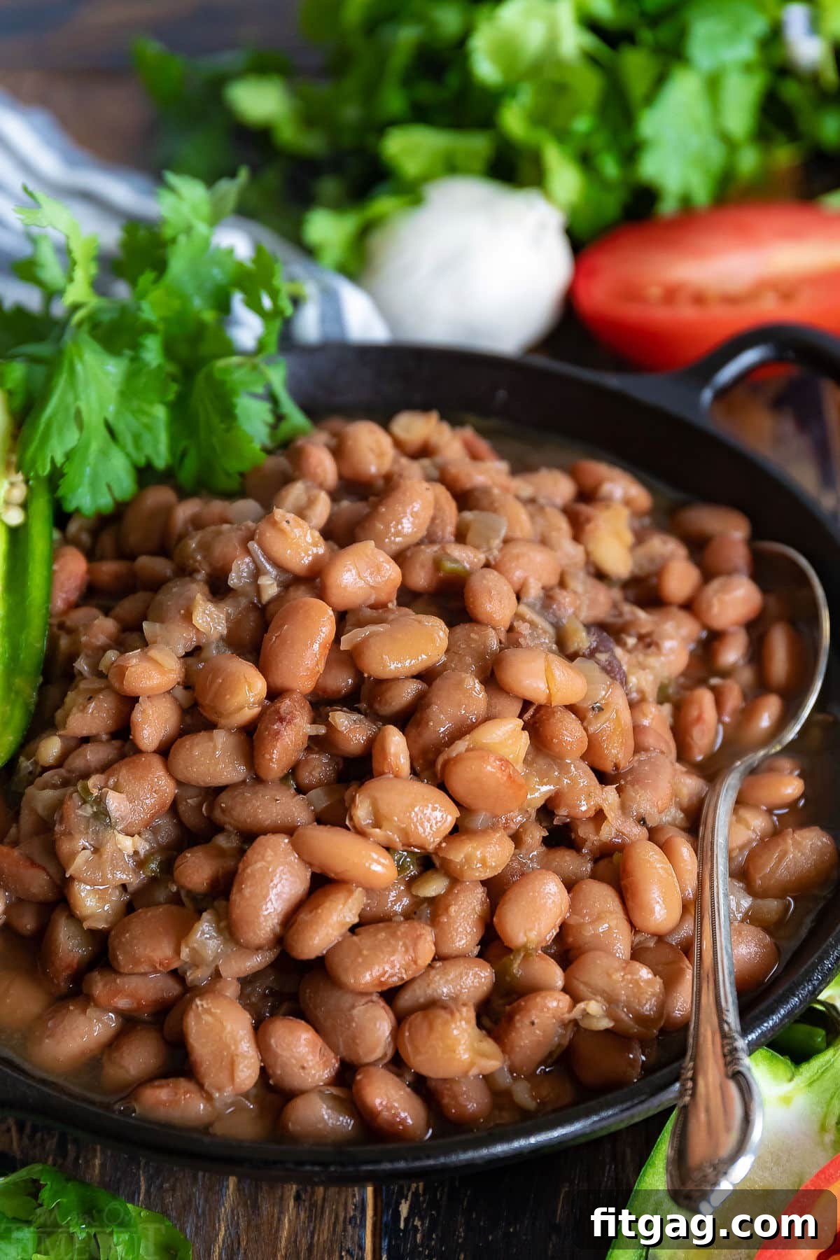 Slow cooker pinto beans served in a black bowl, garnished with fresh jalapeño slices and cilantro.