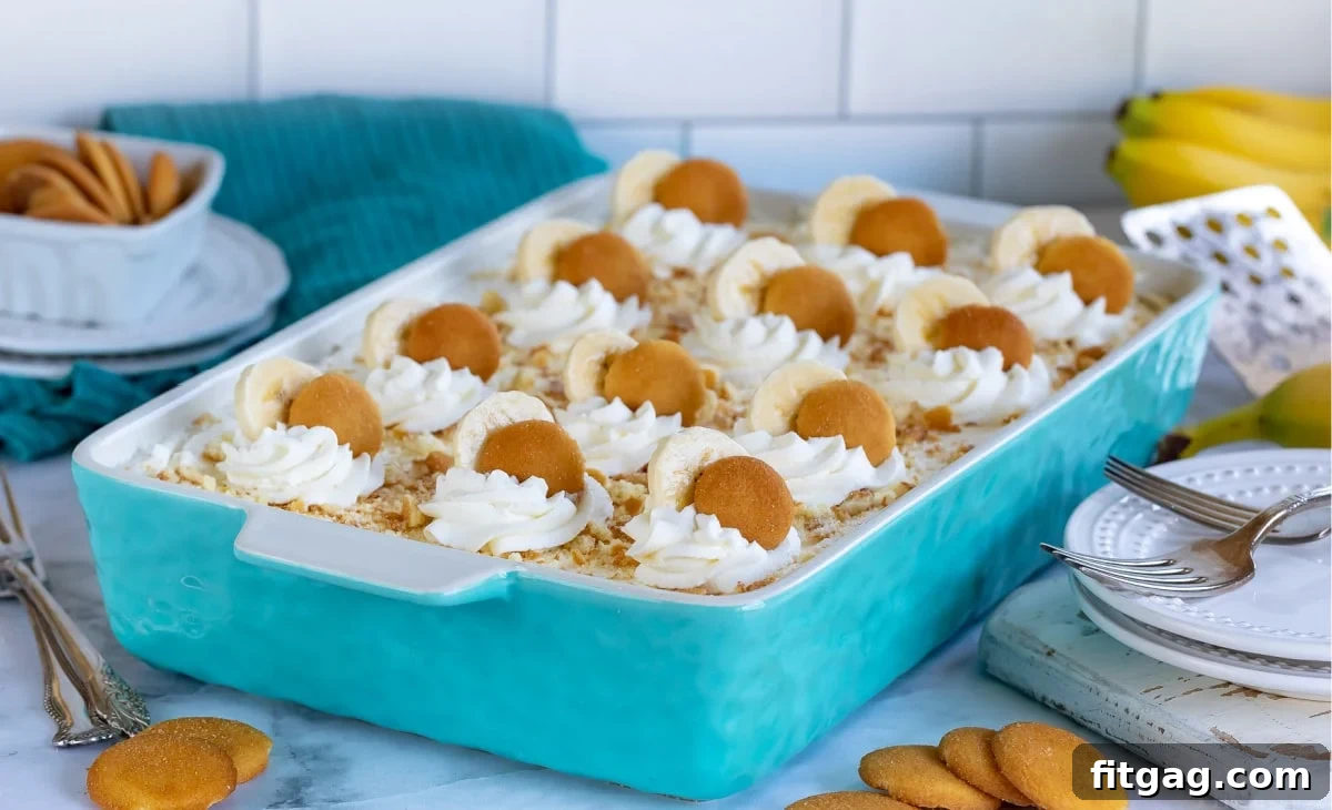 Banana pudding in baking dish topped with dollops of whipped cream, banana slices, and Nilla wafers.