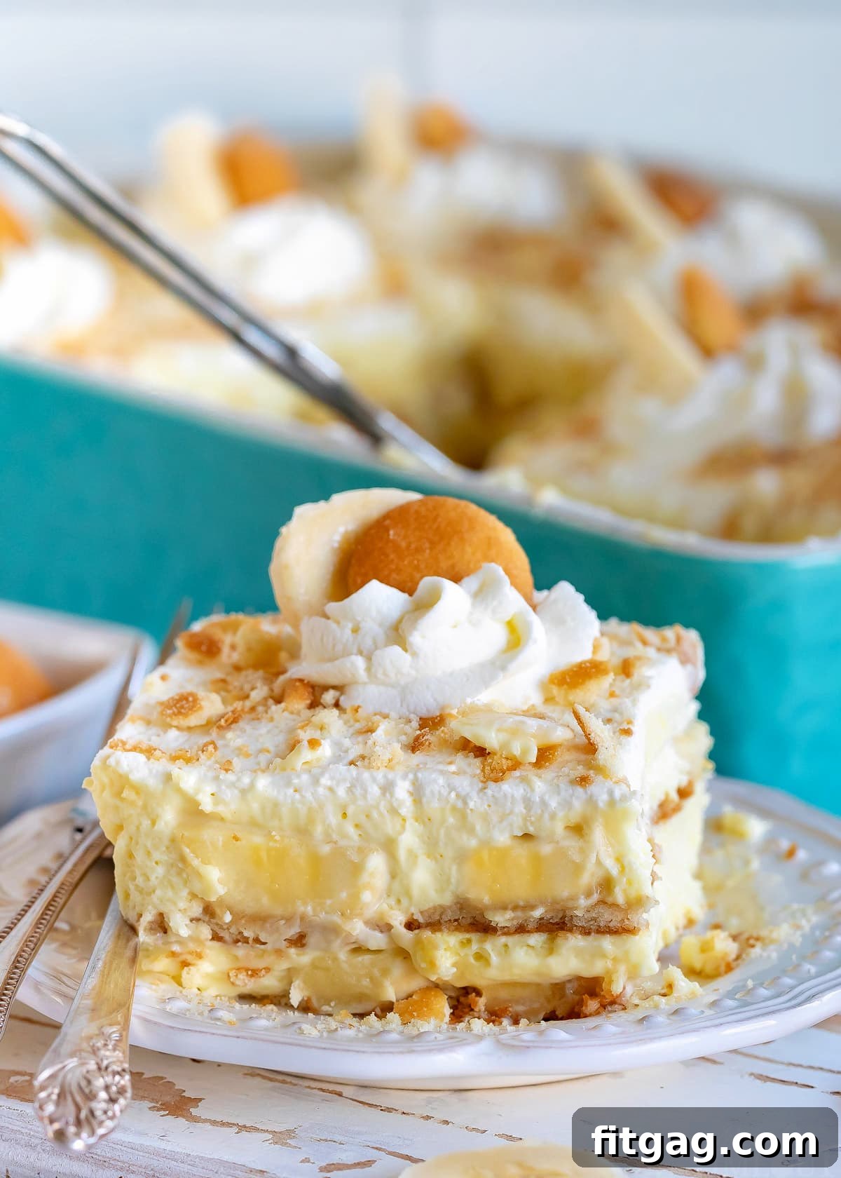 The best banana pudding recipe served on a white plate garnished with whipped cream and Nilla wafers.
