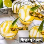 pineapple margaritas on marble cutting board with pineapple in the background square