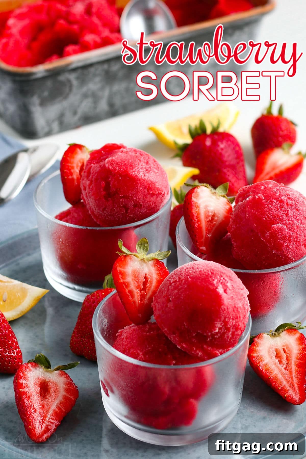 Ruby Frost 2 Bright red strawberry sorbet in small glass jars, garnished with fresh strawberry slices, sitting on a gray plate – a perfect summer dessert.