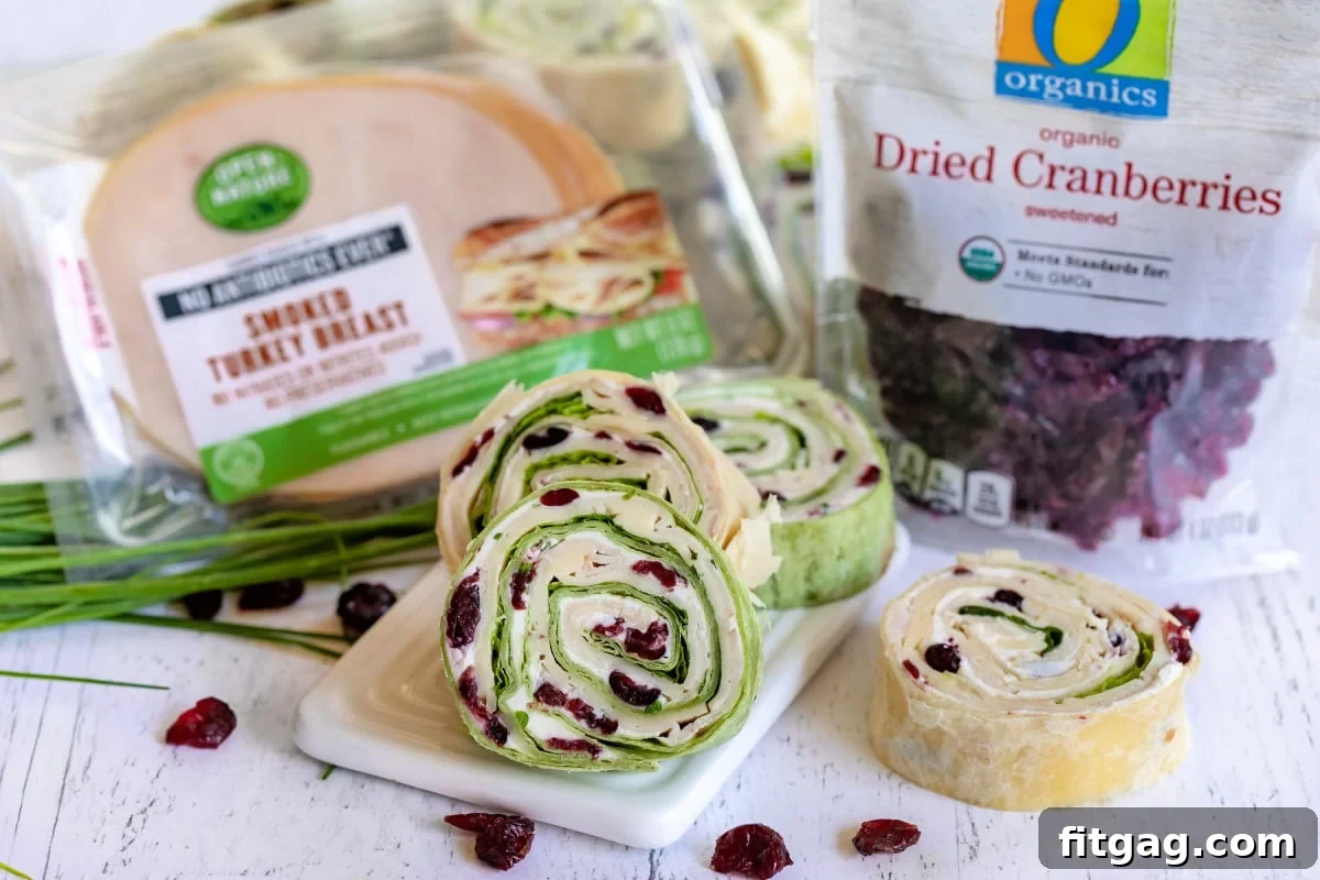 turkey cranberry pinwheels on small white board with packages of turkey meat and dried cranberries on the sides