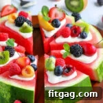 watermelon pizza recipe with a variety of fresh fruit on top cut into wedges on board square