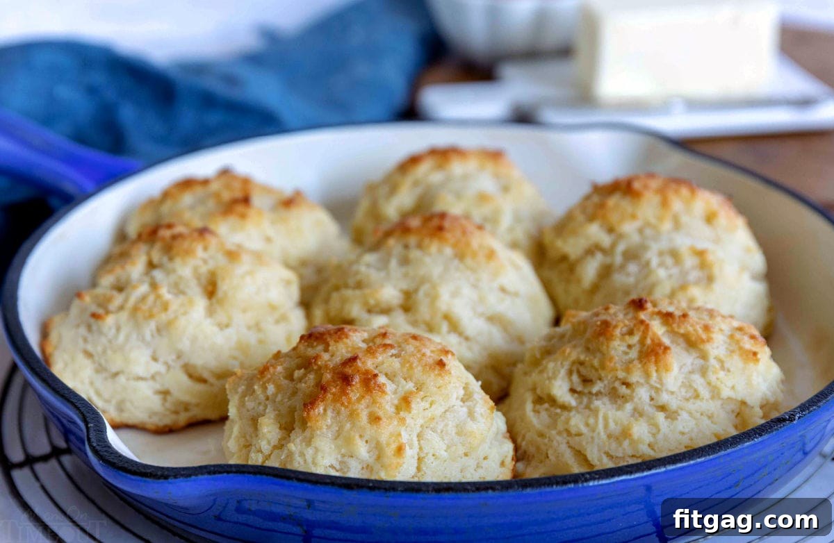 Golden brown buttermilk drop biscuits baked to perfection in a cast iron skillet, showcasing their rustic, fluffy texture.