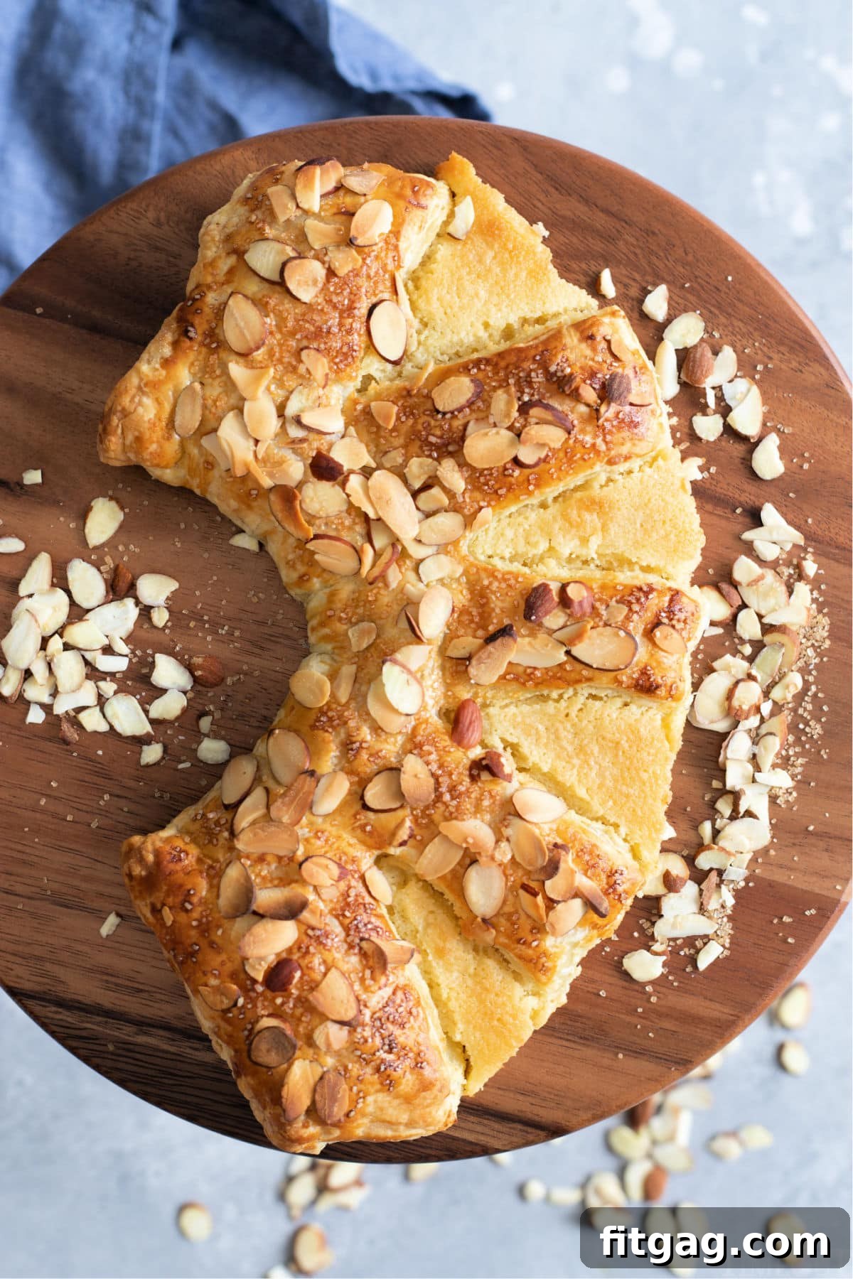 Effortless Almond Bear Claws 2 top down view of almond bear claw on cake pedestal with blue napkin underneath, highlighting a delicious homemade pastry