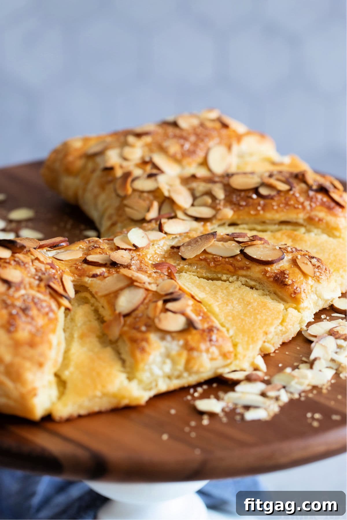 Effortless Almond Bear Claws 4 Almond Bear Claw recipe on white cake stand with wood top, showcasing golden-brown perfection
