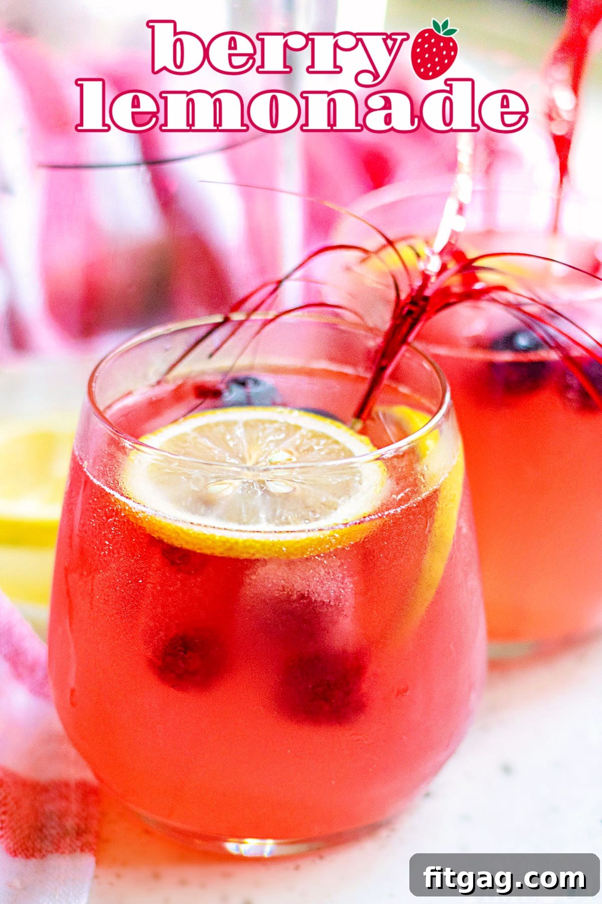 A glass of vibrant berry lemonade garnished with fresh lemon slices, perfect for summer.