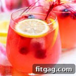 berry lemonade in a wine glass garnished with lemon slices