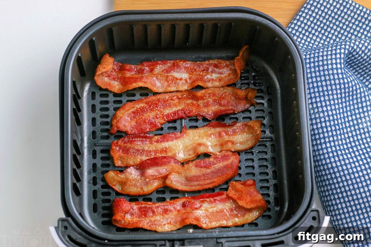 Cooked bacon strips resting in an air fryer basket.