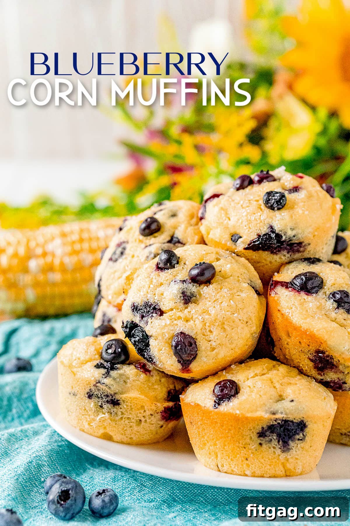 Golden Blueberry Cornbread Muffins 2 Piled high blueberry corn muffins on a white plate with a blue napkin