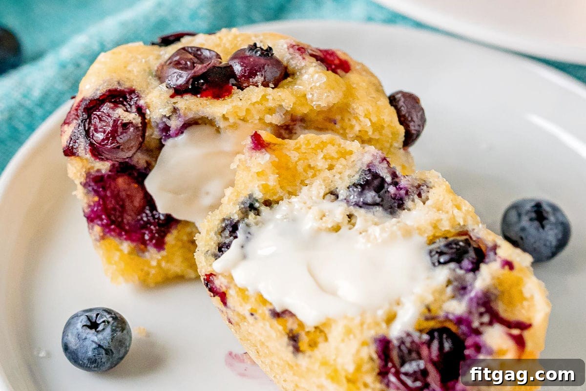 Golden Blueberry Cornbread Muffins 5 Corn muffins with blueberries, split in half and buttered, on a white plate