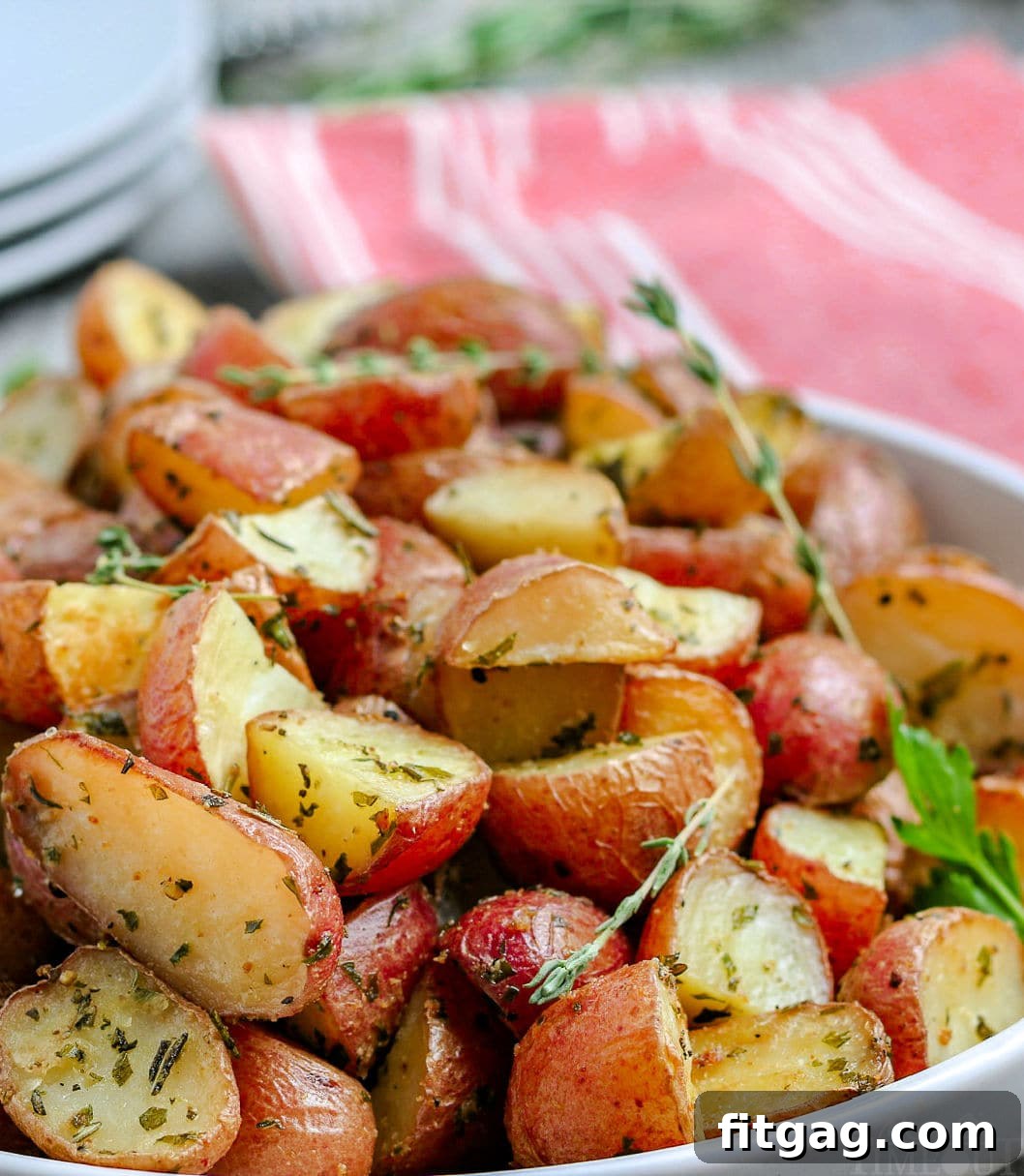 roasted potatoes recipe close up in white bowl with stack of plates in background