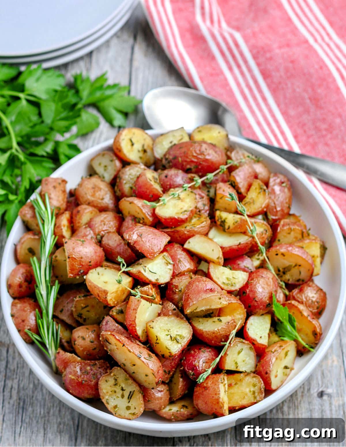roasted red potatoes on white plate sitting on red and white striped towel