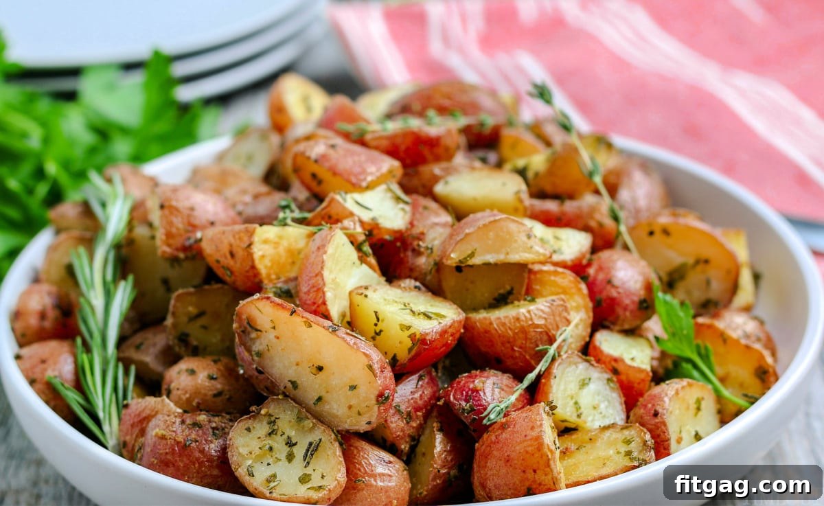 oven roasted potatoes in white bowl with fresh herbs on top wide shot