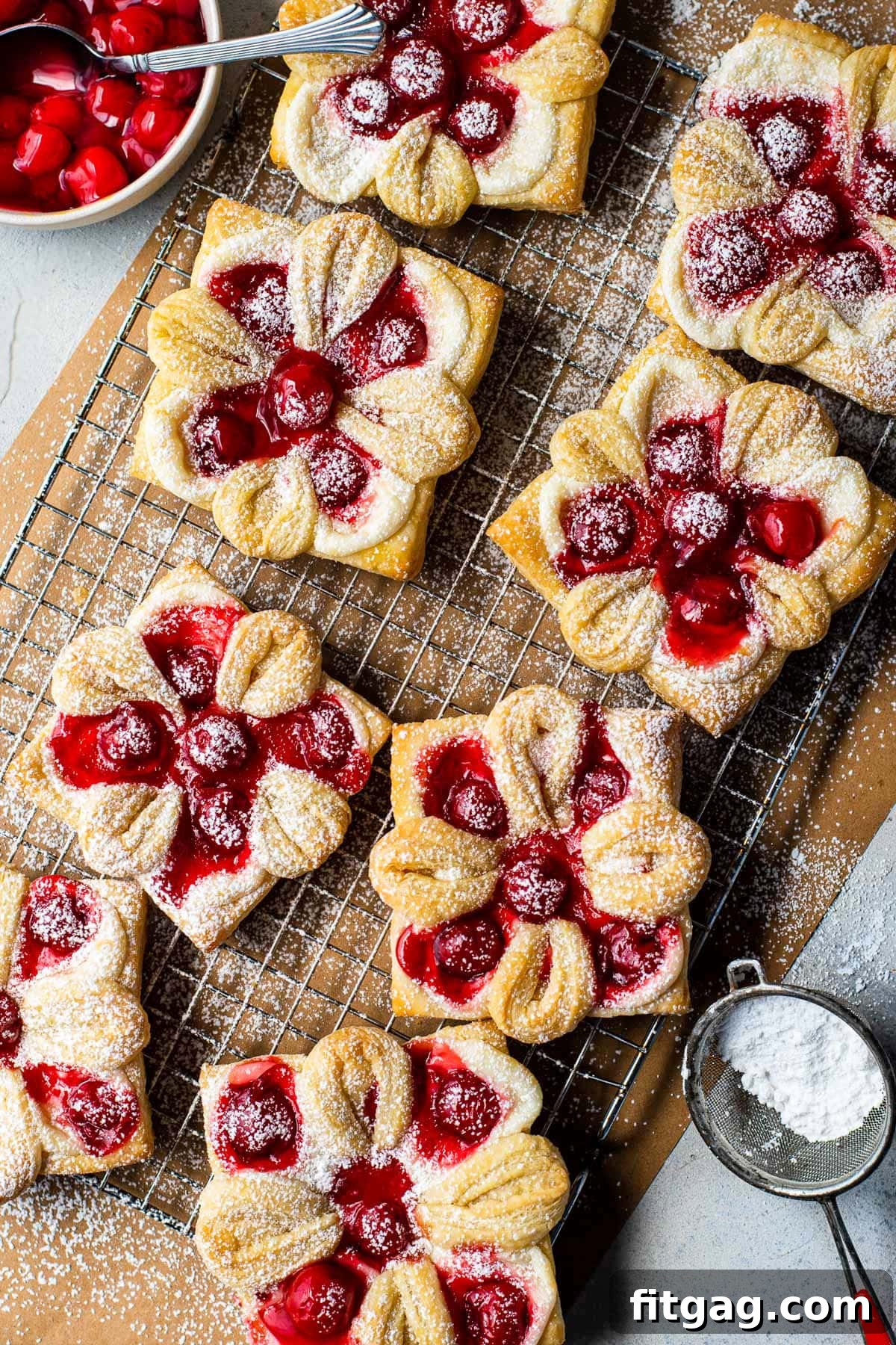 top down view of cherry danishes on brown parchment paper with powdered sugar sprinkled over the top