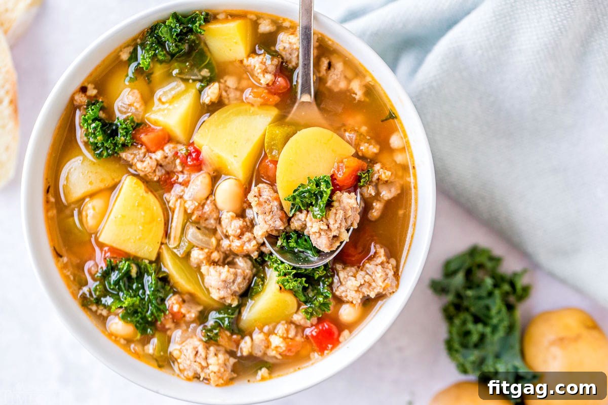 Close-up aerial view of a bowl of sausage kale and white bean soup, served with a decorative napkin.