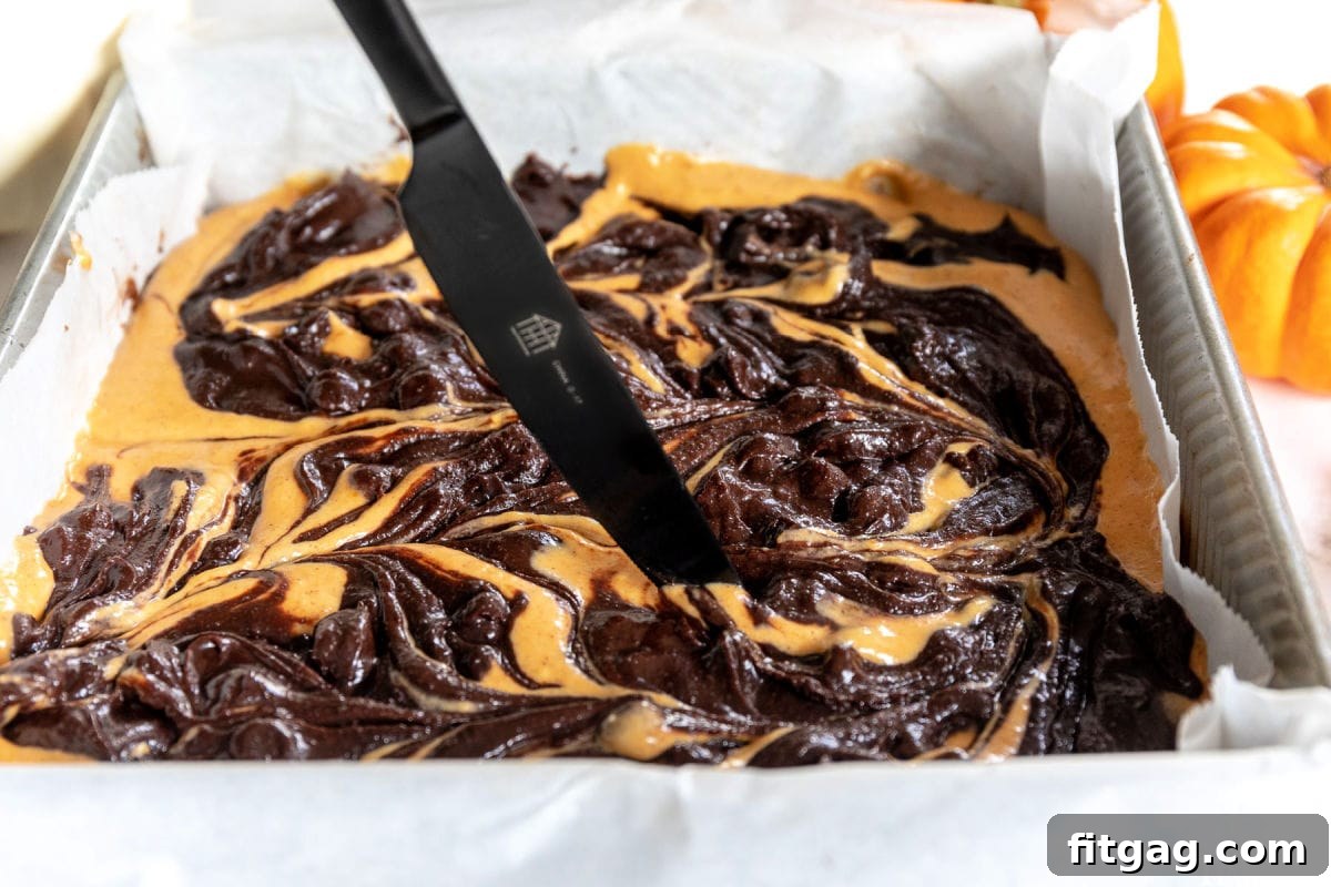 Creating swirls on brownie batter with a black knife, showing the marbled effect.