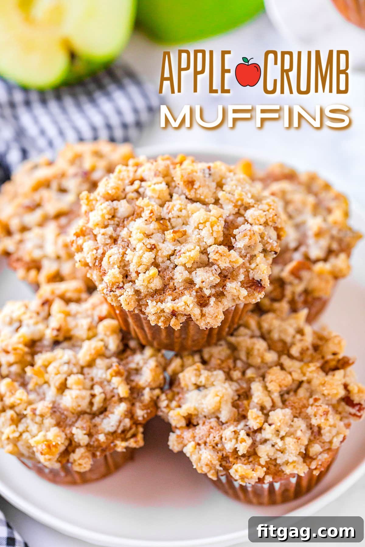 Five beautifully arranged apple crumb muffins on a white plate, nestled beside a charming blue and white striped napkin. The muffins feature a golden-brown top with a generous pecan streusel.
